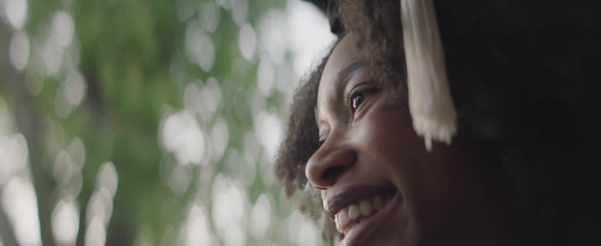 Young woman wearing a graduation cap smiles while looking into the distance