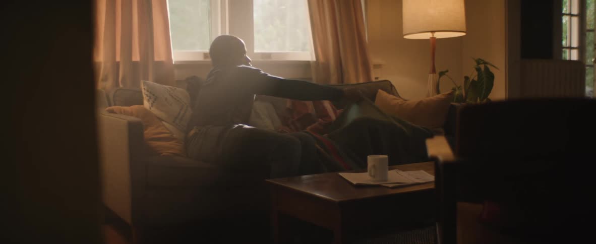 Man adjusting the blanket while lying with his wife and daughter on the living room sofa