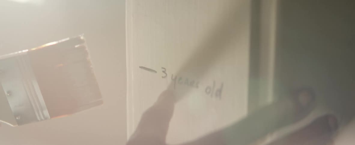 A man races his finger on the wall near some writing