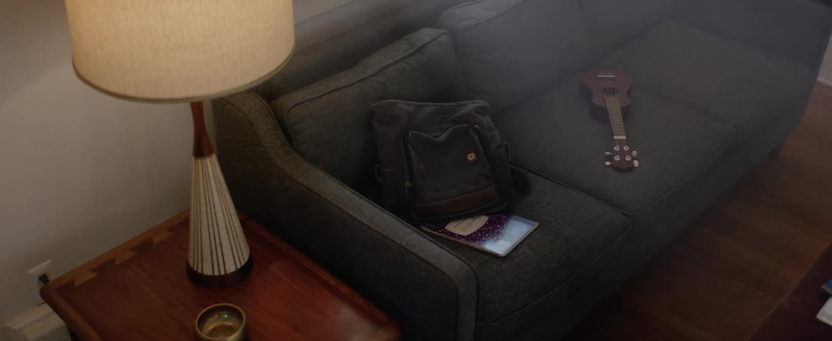 A bag and guitar are on a sofa