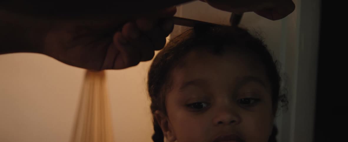 A young girl looks up as someone marks her height with a ruler against a doorway
