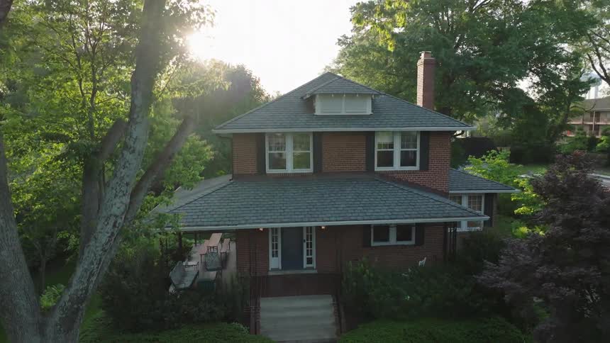 A large green tree is in front of the home