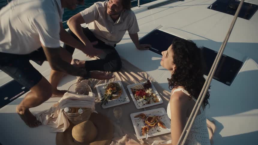 Man serving a couple a picnic on board a boat