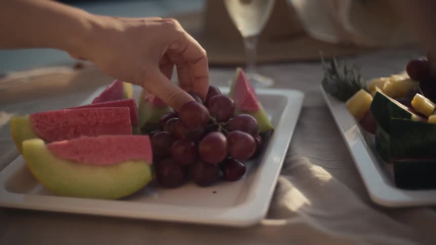 A person plucks a grape off a plate