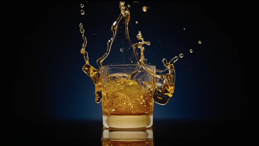 An ice cup falls into a glass