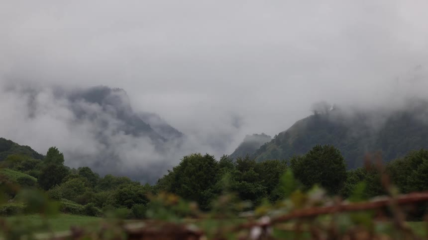 Smoke rising from the ground in a grassland surrounded by mountains at midday