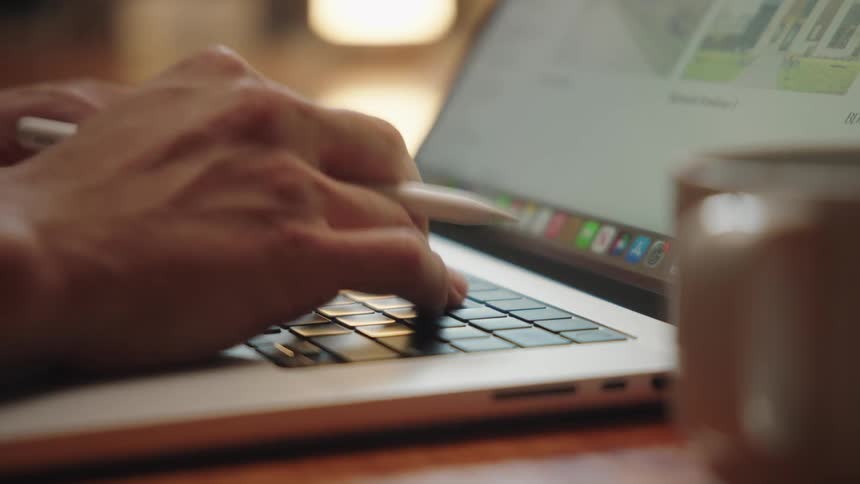 Person uses a stylus to make notes on a tablet while using a laptop