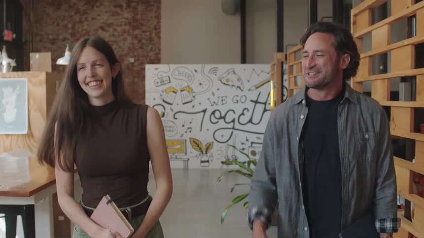 Man and woman walking together in a work environment smiling