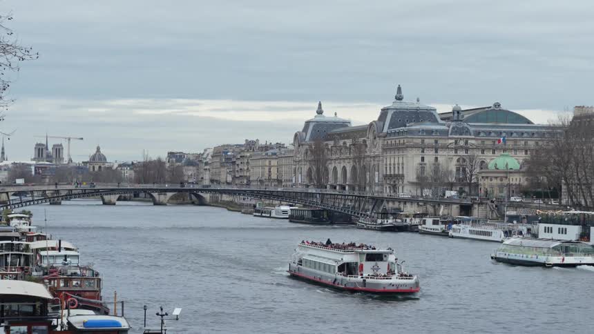 Ferries pass each other while traveling along a river past docked boats on a cloudy autumn day