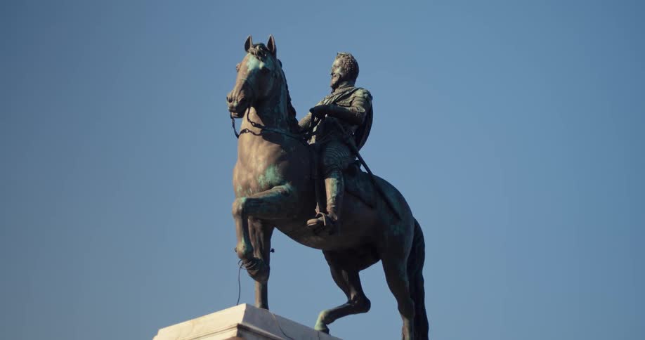 Man riding a horse in a bronze statue and against a blue sky