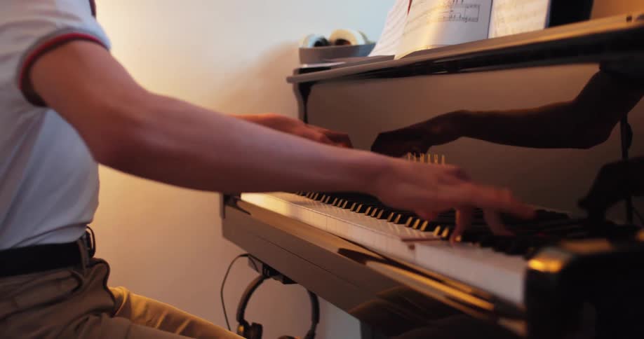 Person playing the piano with sheet music placed on the instrument