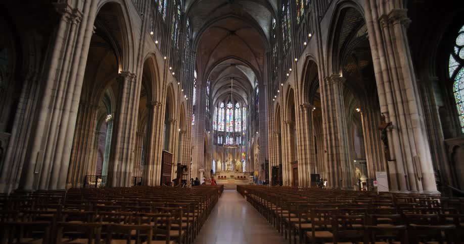 People sit in a mostly empty cathedral during the daytime