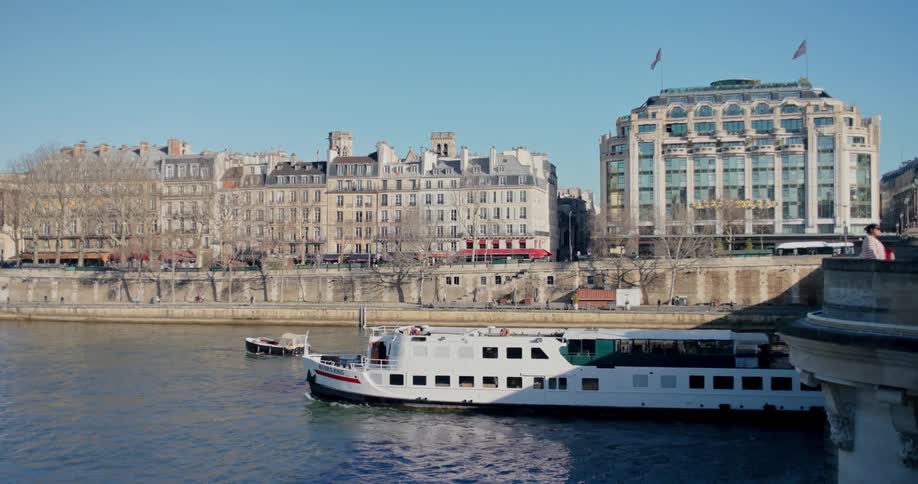 Tourist boat traveling through a sea canal with a classic city in the background