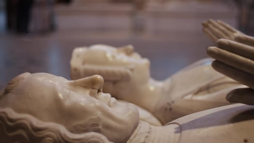 Two white statues lying in an interior space