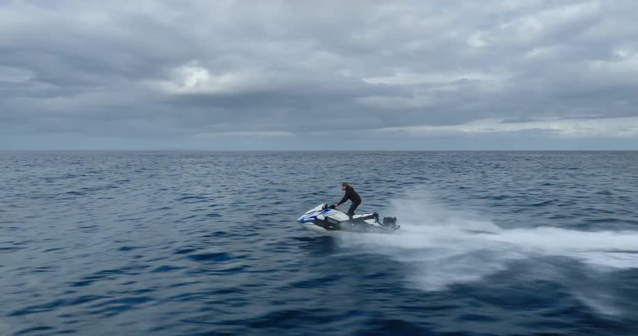 A person riding a jet ski in the ocean at midday on a cloudy day