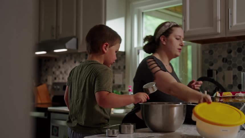 Boy in the kitchen helping his mother cook between the pots