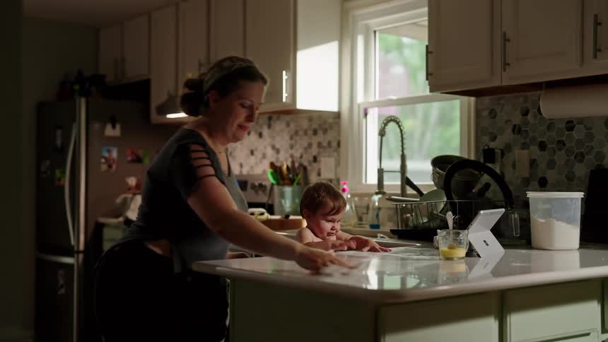 Mother starting to cook with her little daughter sitting at the table