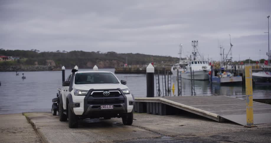 Person steers his vehicle backwards down a ramp while launching a boat on an overcast day