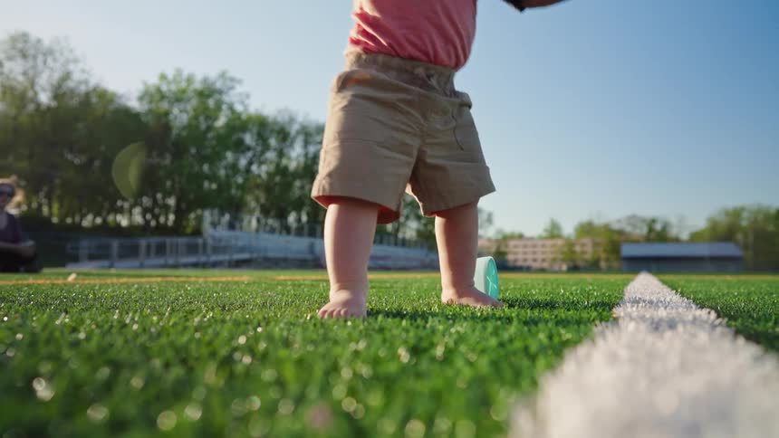 A barefoot childs feet are shown playing with a toy on a grassy field with a white line