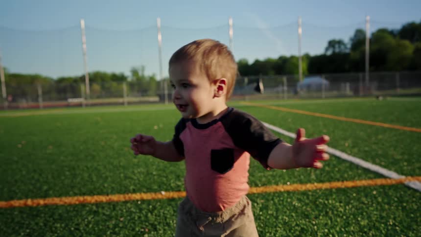 Small child balancing while walking on artificial grass