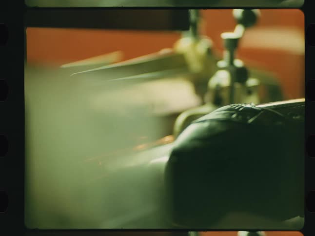 A small machine that is cutting a piece of metal creating sparks that fly off to the side in a workshop