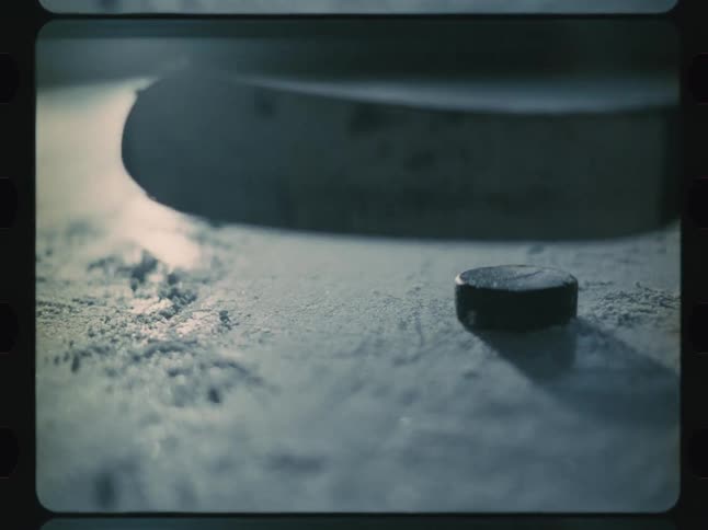 A hockey stick is hitting a hockey puck on ice