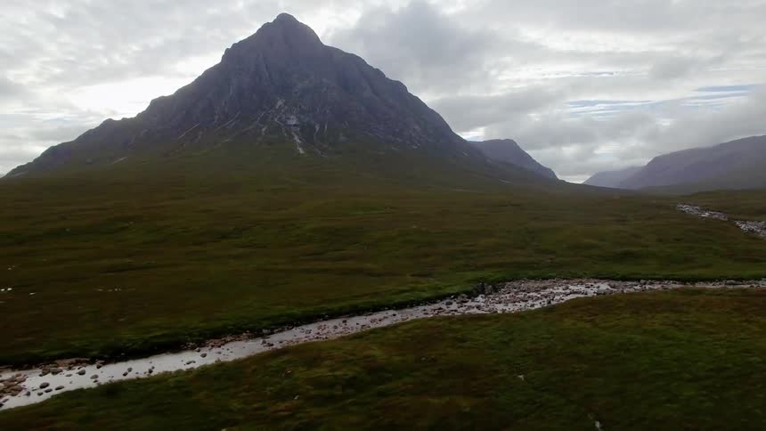 Water flows through a canal in front of a mountain