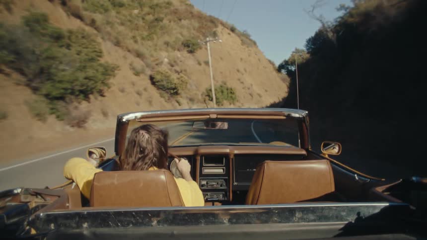A mana is driving his convertible down the windowing road
