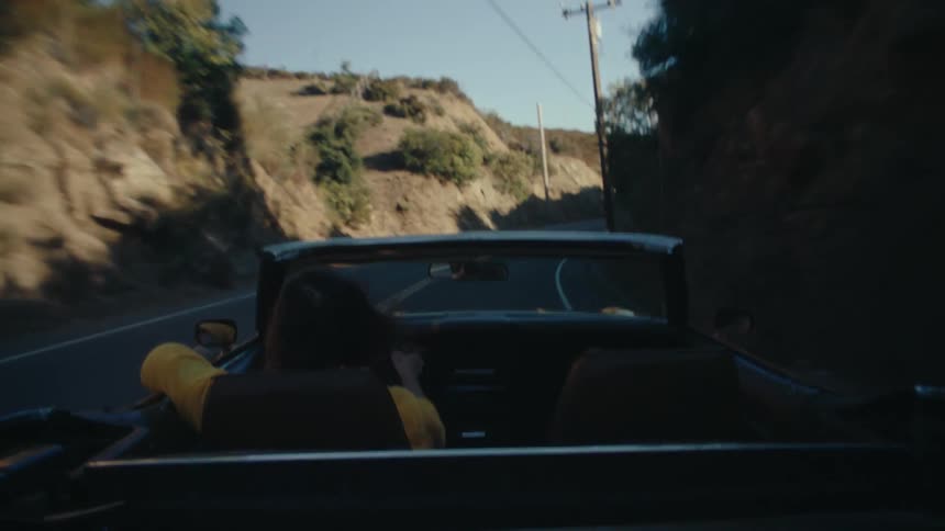 Person driving a convertible on a hillside road