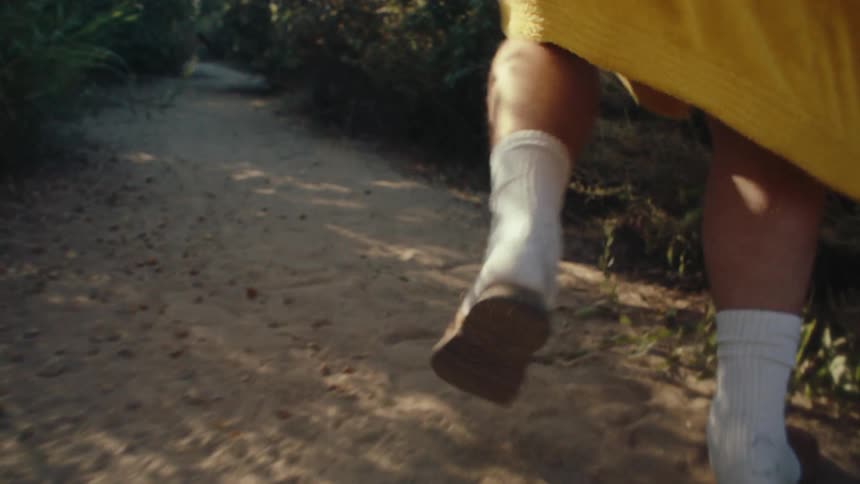 Legs of a man in socks and flipflops running along a trail