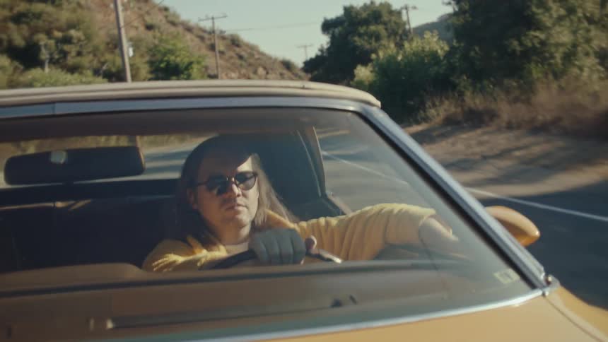 The man hands his arm out the window as he drives