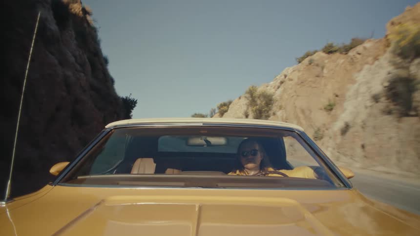Man drives his car along a highway passing between rocky hills