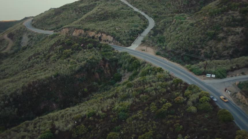 Yellow convertible car traveling down a mountain road