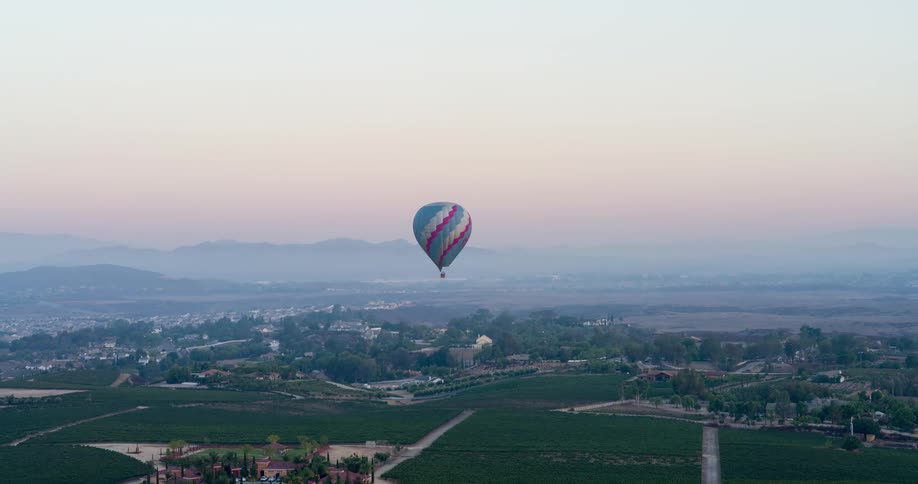 The hot air balloon flies over the long field