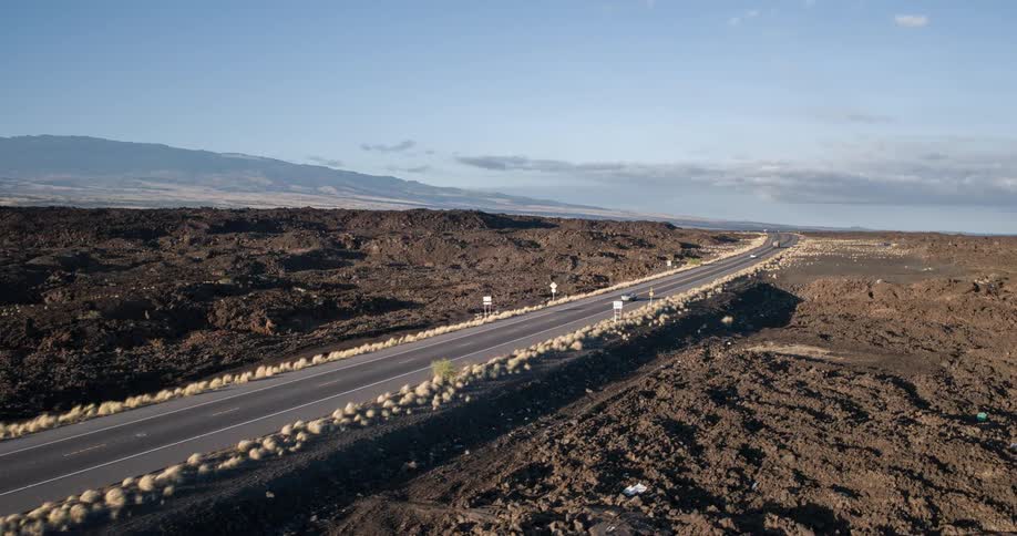 Cars travel down a freeway that is surrounded by dirt and mountains
