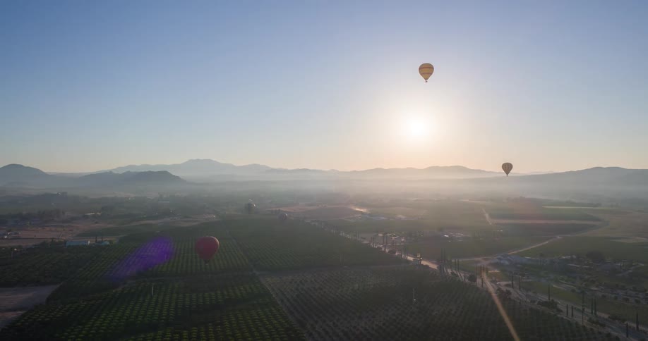 Aerial panorama of balloons flying with the sun on the horizon