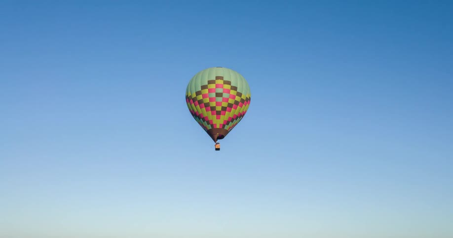 Hot air balloons float above a residential neighborhood on a summer day