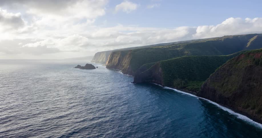 An aerial view of a vast green coastline meeting the deep blue ocean