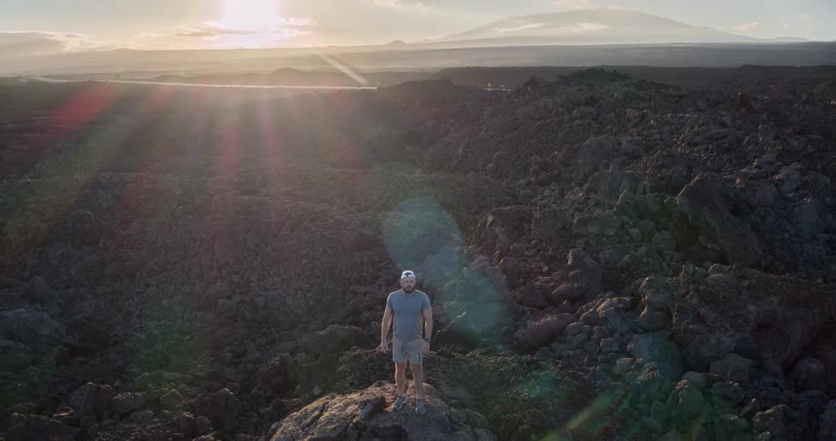 Man standing on volcanic rocks during sunset