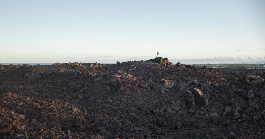 Person on a rock in the late afternoon with the sea on the horizon