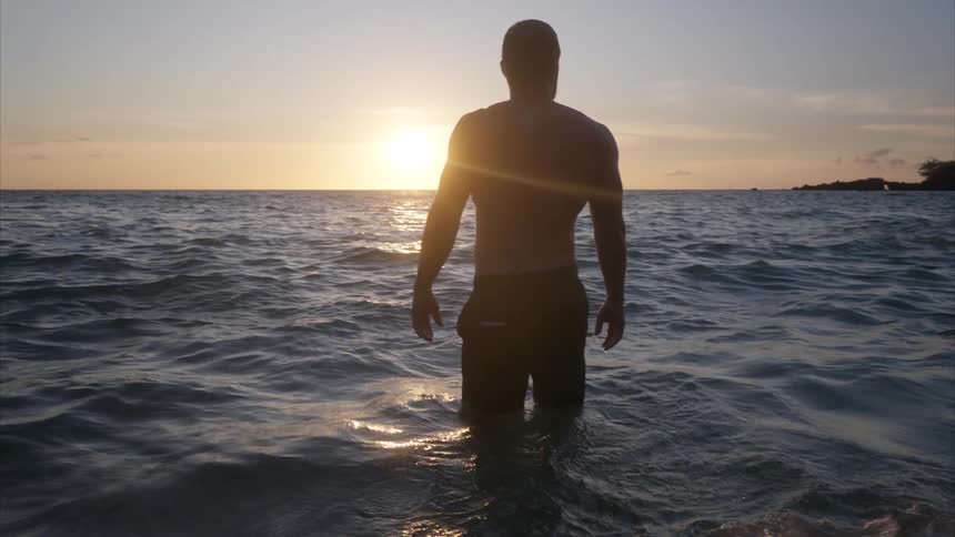 Man walking in the sea during sunset