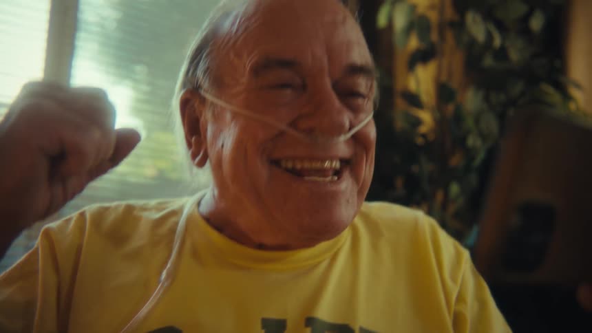 An elderly man cheers for joy while looking at the smartphone in his hand
