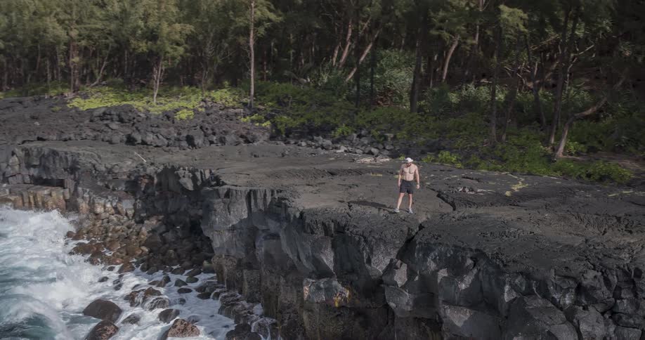 A man swings his arm on the cliff of the ocean