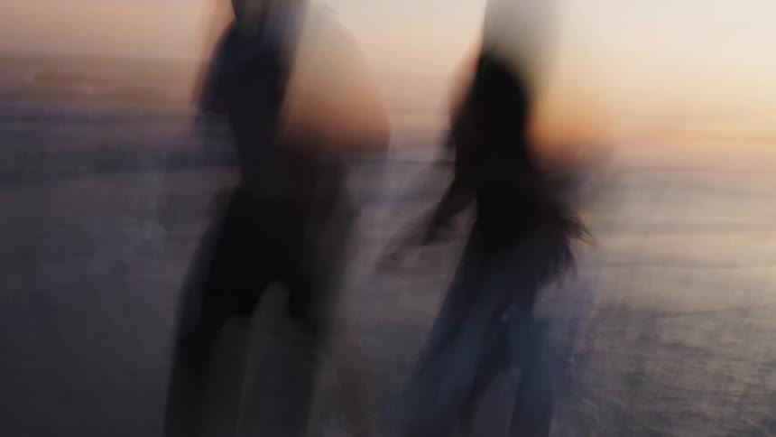 A couple runs along the shoreline of a beach in super fast chaotic motion