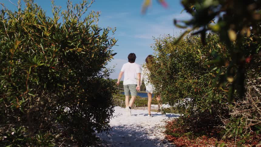 A couple run on the beach and stop and hug