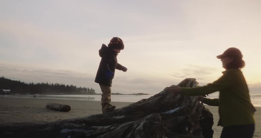 A boy climbs up the stone on the beach