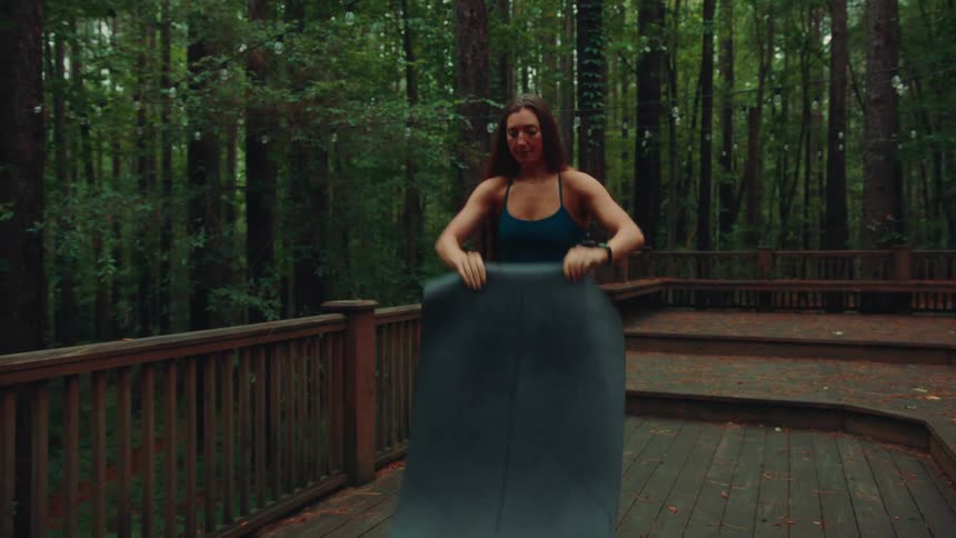 A woman sets up to do yoga on the deck