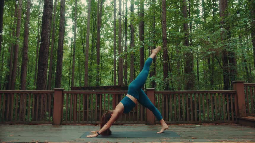 A woman performs several yoga stretches outdoors while surrounded by a forest