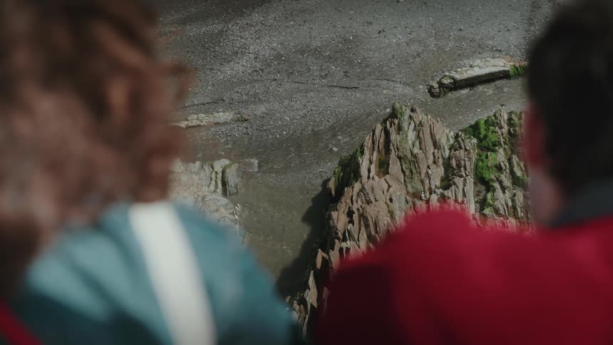 Two people observing rocks and sand from above