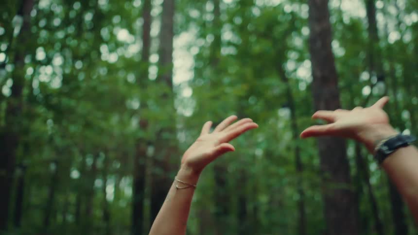 A woman stretches while on a patio located in a forested area